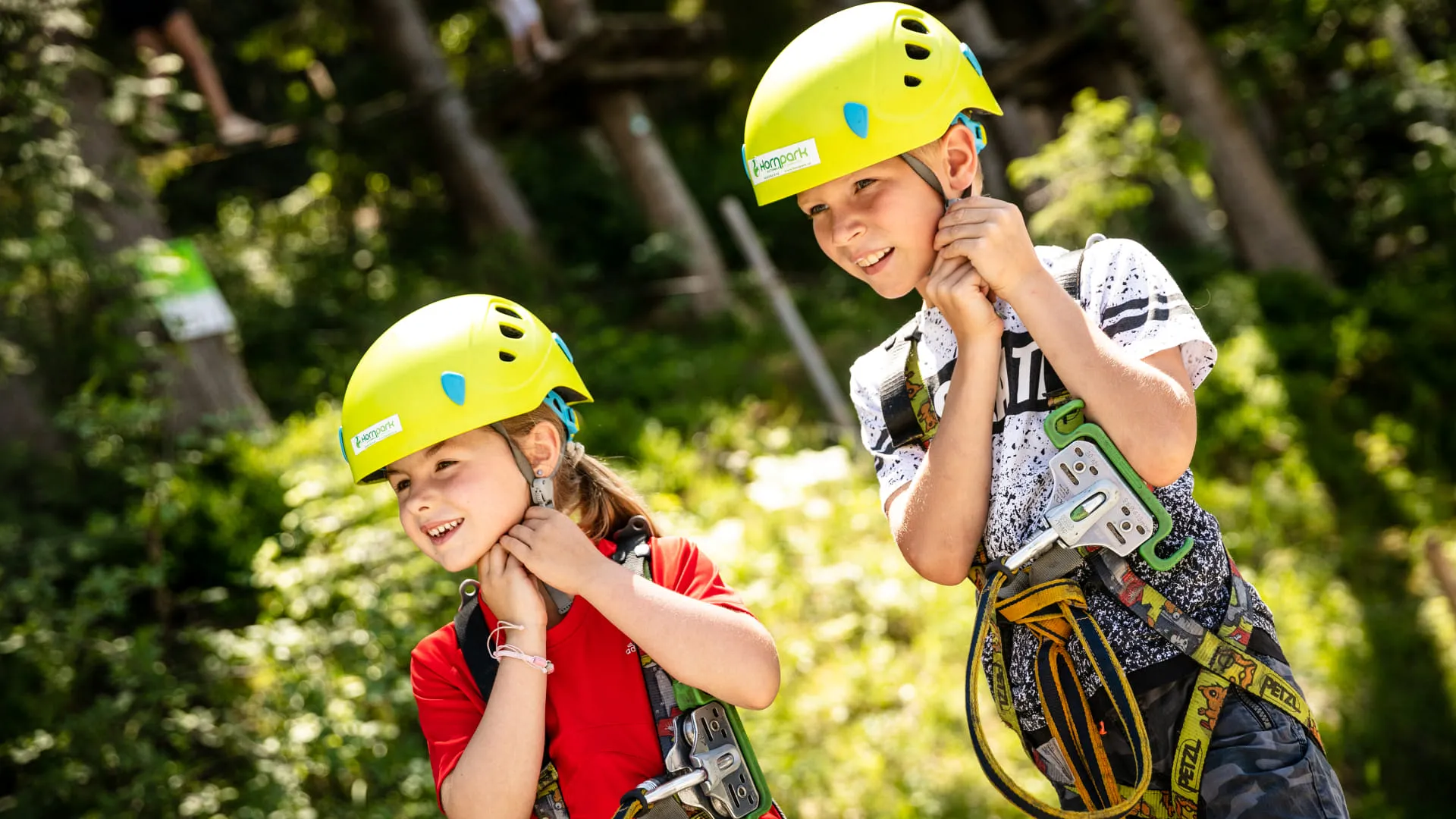 Zwei Kinder mit gelben Helmen und Kletterausrüstung