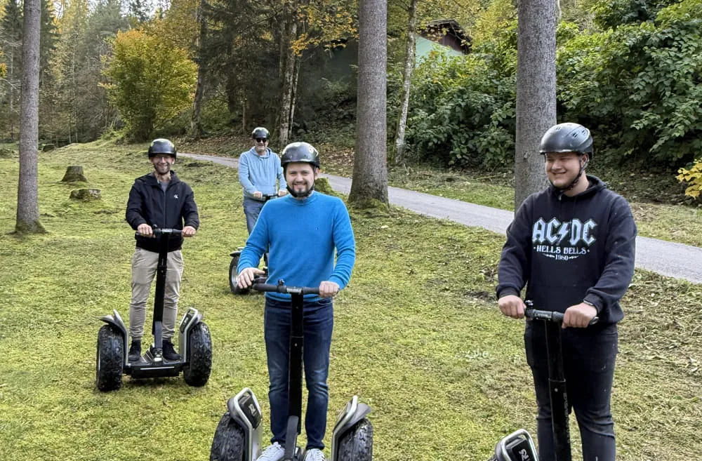 Fünf Personen fahren auf Rollern im Wald