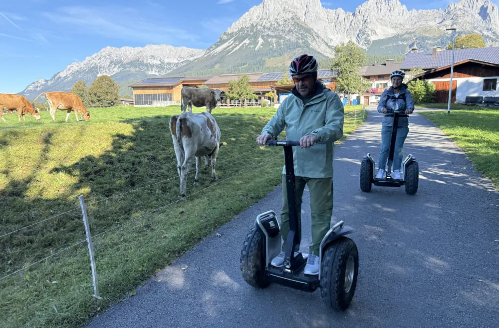Zwei Personen fahren auf Segways in alpiner Landschaft.