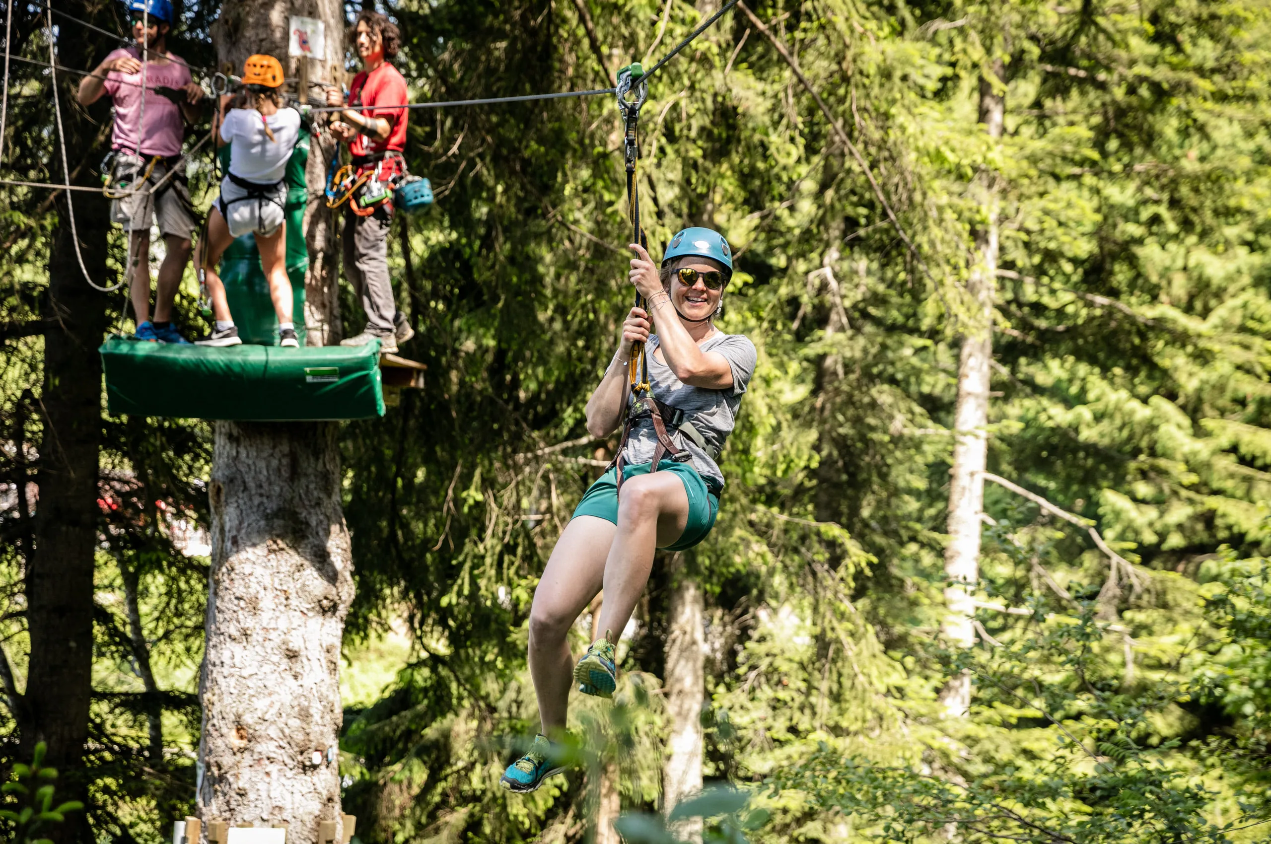 Person schwingt an einer Seilrutsche im Wald.