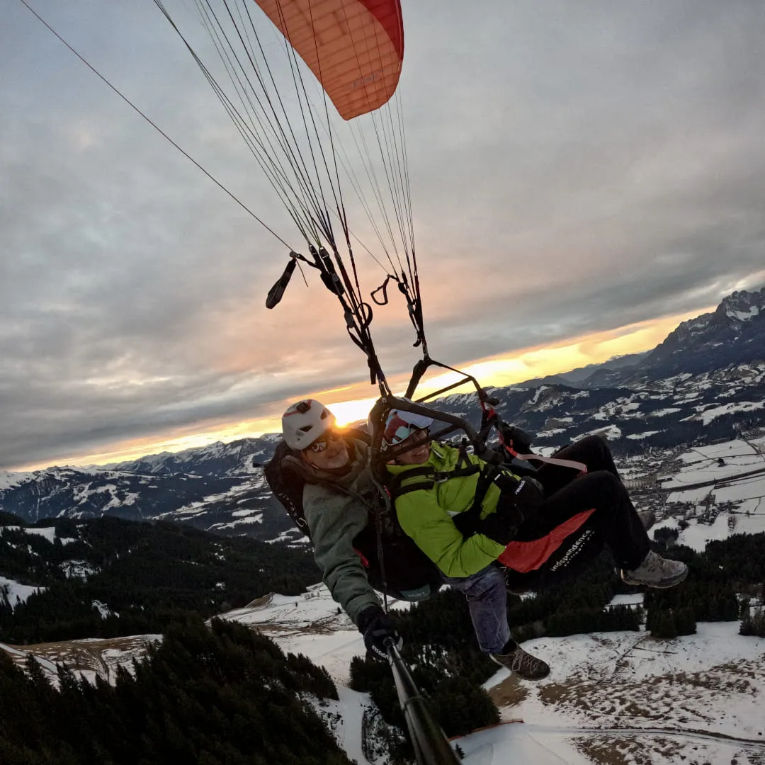 Gleitschirmfliegen über schneebedeckte Berge bei Sonnenuntergang