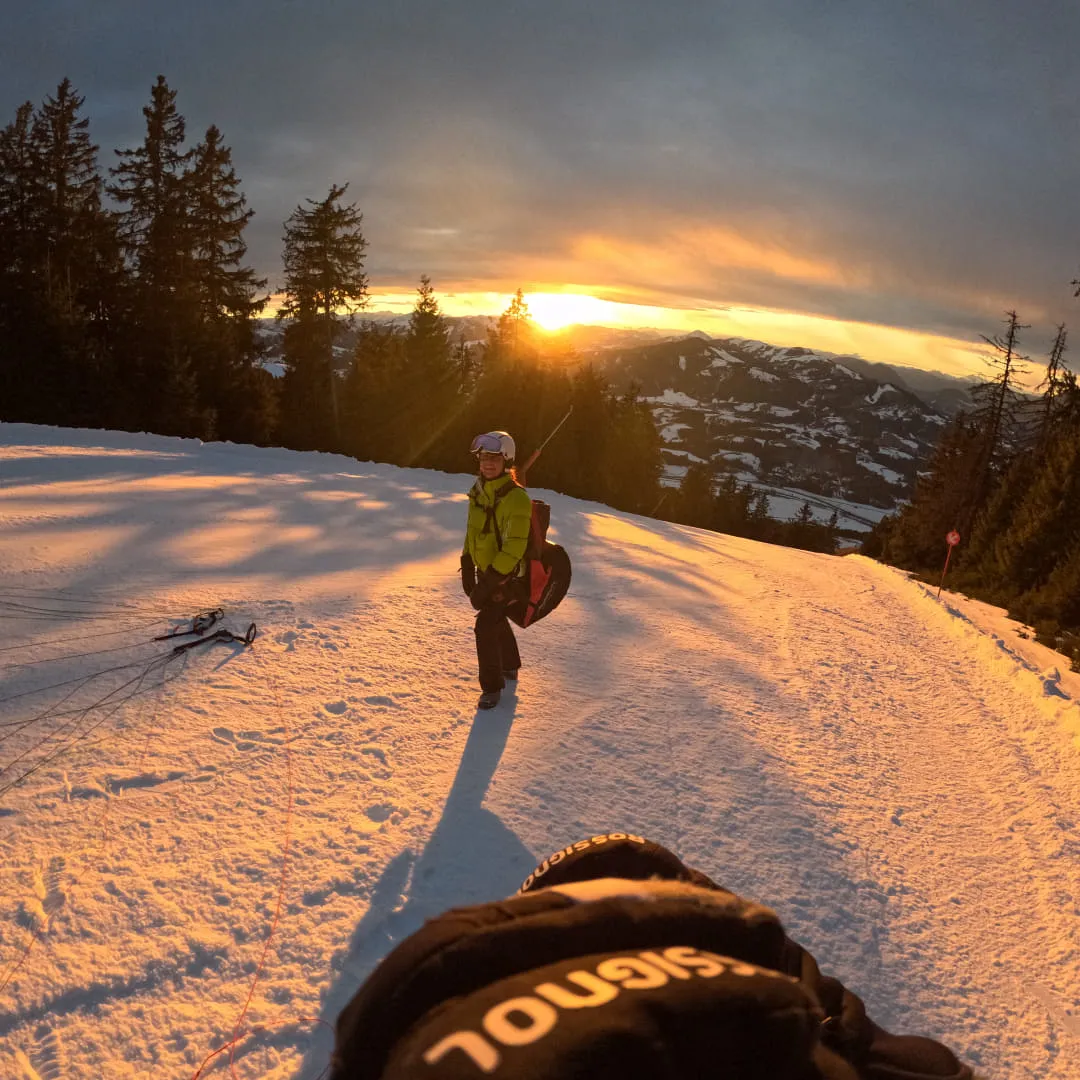 Person auf verschneitem Hang bei Sonnenuntergang
