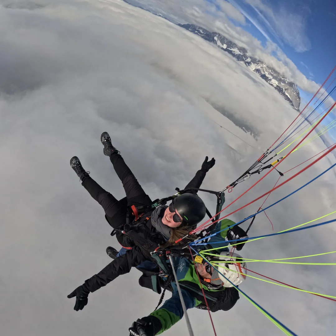 Tandem-Gleitschirmfliegen über Wolken und Bergen