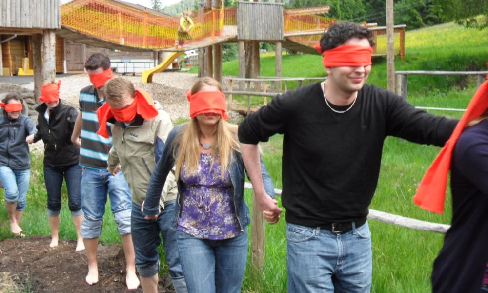 Gruppe von Menschen mit verbundenen Augen in einem Garten
