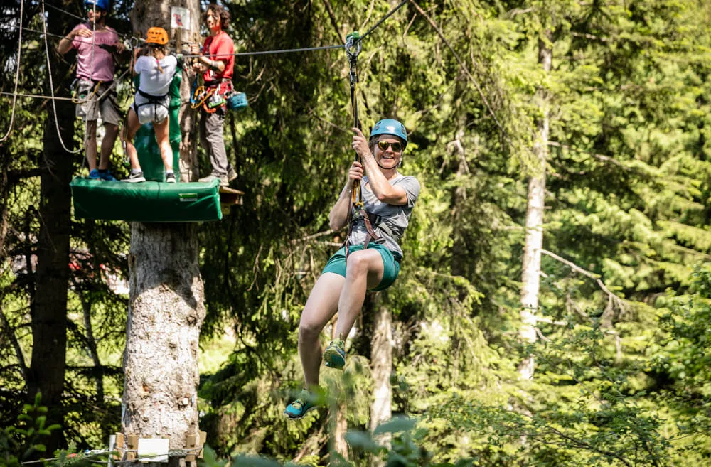 Person schwingt mit Seil durch Bäume in St. Johann.