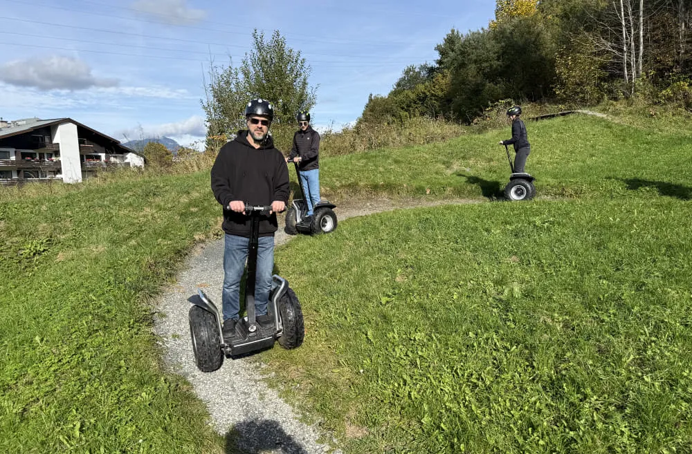 Drei Personen fahren auf Segways in einer Landschaft.